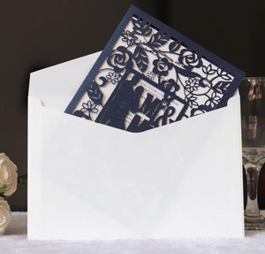 Detailed laser-cut wedding invitation featuring elegant navy blue floral patterns and envelopes