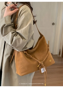Close-up of tan suede hobo bag with braided drawstring detail and PAN 'TOR logo tag