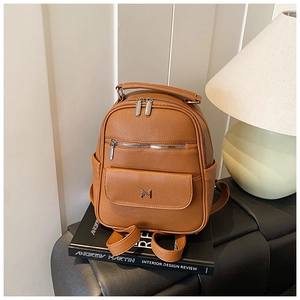 Close-up of caramel brown mini backpack with pebble texture and M metal buckle detail