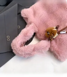 Détail d'un sac cabas rose en fausse fourrure avec un petit pendentif ours brun