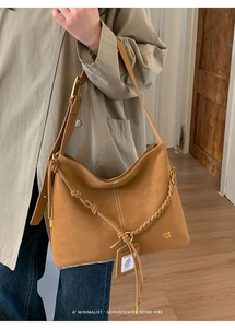 Detail view of brown leather hobo bag with white contrast stitching and PAN TOR gold logo
