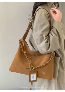 Detail of caramel brown bucket bag featuring braided rope knot and gold hardware