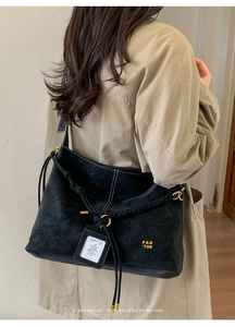 Detail of black textured bucket bag with woven drawstring and gold metal hardware
