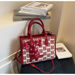 Detail of red bridal tote bag with Xi character jacquard pattern and silk ribbon
