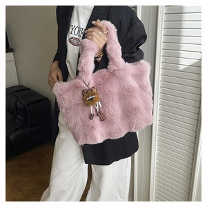Détail d'un cabas en fausse fourrure rose avec breloque en peluche sur une tenue