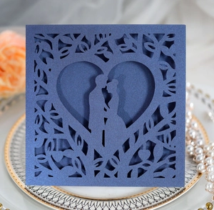 Macro view of navy blue laser-cut wedding invitation card with heart and kissing couple
