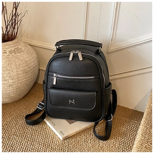 Detail of black lychee grain leather mini backpack with dual zippers and metal logo