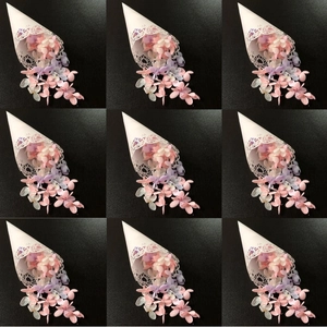 Nine laser-cut white lace paper cones filled with colorful flower petals for wedding decor