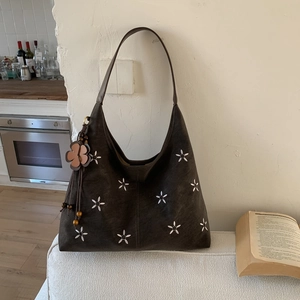 Gros plan détaillé d'un grand sac cabas marron foncé avec broderie florale blanche délicate