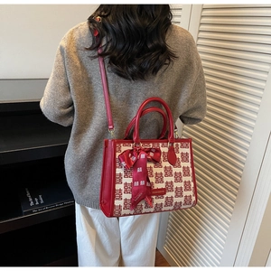 Detail of red wedding handbag with traditional patterns worn by a model in a modern room