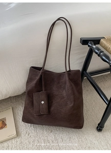 Close-up of deep brown vintage tote bag with matte texture and matching small pouch