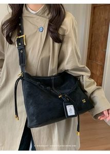 Close-up of vintage black faux suede tote bag featuring white contrast stitching and braided detail