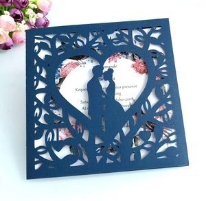 Detail of laser-cut navy blue wedding invitation with heart-shaped tree and couple silhouette