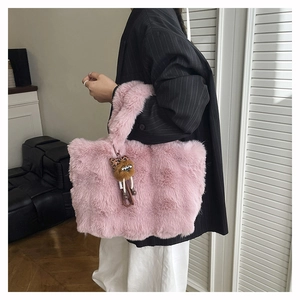Détail d'un cabas en fausse fourrure rose avec large poignée et un pendentif ours en peluche