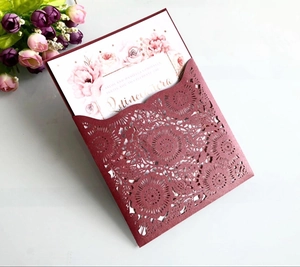 Macro view of burgundy laser-cut invitation with floral patterns and watercolor roses