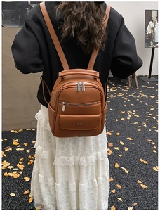 Brown litchi pattern PU leather backpack shown on a model in an outdoor autumn setting