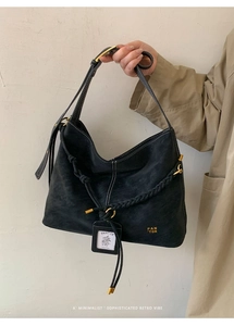 Detail of black matte hobo bag featuring braided rope decor and vintage gold hardware