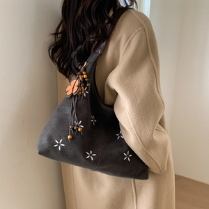 Détail du sac cabas vintage avec broderies florales blanches et pendentif en perles