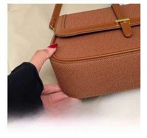 Detail shot of precise stitching and leather trim on a brown cross-body bag