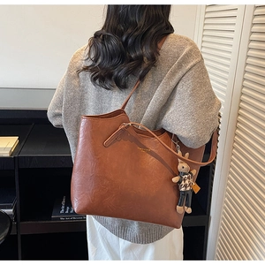 Detailed view of large brown retro leather tote bag with a cute rabbit charm accessory