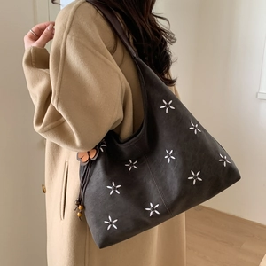 Détail du sac hobo gris foncé avec broderie florale et pompon en perles de bois