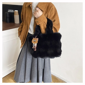 Détail du sac cabas noir en peluche avec un pendentif monstre marron pour le style d'hiver
