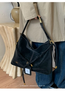 Detail of black suede Hobo bag with woven texture strap and gold hardware accents