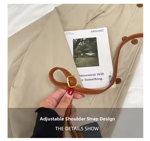 Detail showing the adjustable brown leather shoulder strap with a golden metal buckle