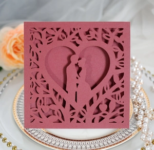 Detail of laser-cut heart wedding invitation with romantic silhouette on ceramic plate