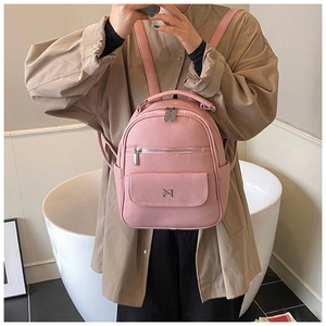 Detail of pink textured leather mini backpack with metal M logo and multiple pockets