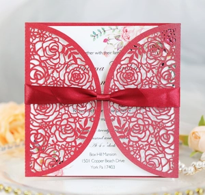 Detail of laser cut red rose wedding invitation with elegant silk ribbon bow