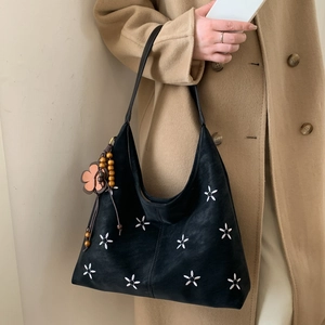 Détail du sac cabas noir en daim avec broderies fleurs blanches et charm de perles