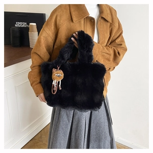 Détail d'un sac cabas noir en fausse fourrure douce avec un petit lion en peluche marron