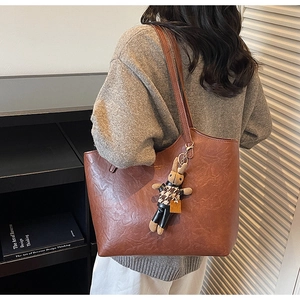 Detail view of brown faux leather tote bag with a cute bunny charm on model's shoulder