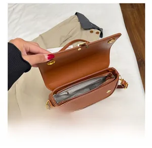 Detail of the brown square bag interior with gold magnetic buckle and zipper pocket