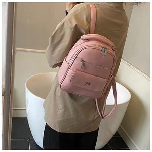 Detail shot of a pink mini backpack in lychee texture leather worn by a model
