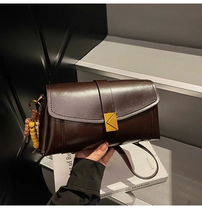 Detailed shot of retro dark brown leather crossbody bag with golden metal triangle lock