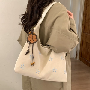 Détail de broderie florale sur cabas beige et pendentif fleur avec perles en bois