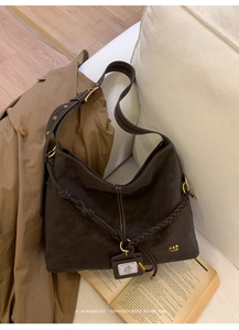 Detail of dark brown textured leather bag with contrast stitching and woven rope trim