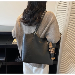 Macro shot of black pebbled leather tote bag with gold lettering and cute bunny pendant