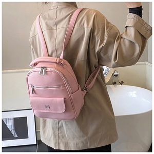 Pink pebbled leather backpack detail with silver M-logo and layered zipper pockets