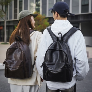 Détail de sacs à dos en simili cuir marron et noir portés par des mannequins en ville