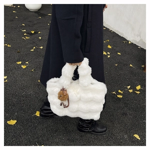 Gros plan du sac cabas en peluche blanche avec texture ondulée et charm d'ours