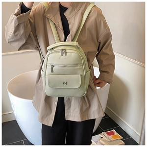 Detail view of light green lychee textured leather backpack with multi-layer zippers