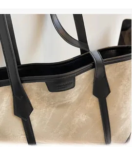 Detailaufnahme der beigen Canvas-Tragetasche mit schwarzen Lederbesätzen und Nähten