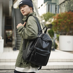 Détail d'un sac à dos en cuir noir avec poche frontale sur un citadin moderne