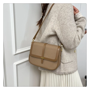 Close-up of brown textured fabric shoulder bag with golden buckle on tweed jacket