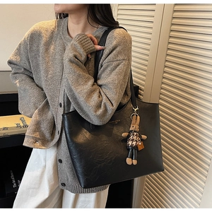 Detail of black tote bag featuring textured leather and cute rabbit plush charm