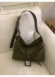 Detail of olive green distressed leather tote with woven trim and vintage bronze hardware