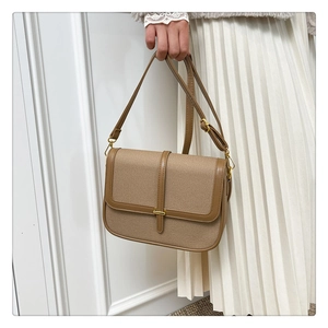Detail of a vintage canvas crossbody bag with brown faux leather trim and golden buckle